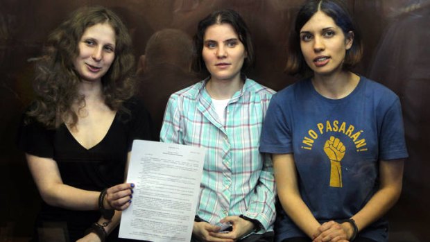Girl power ... Pussy Riot members, from left, Maria Alekhina, Yekaterina Samutsevich, and Nadezhda Tolokonnikova show the court's verdict as they sit in a glass cage at a courtroom in Moscow.