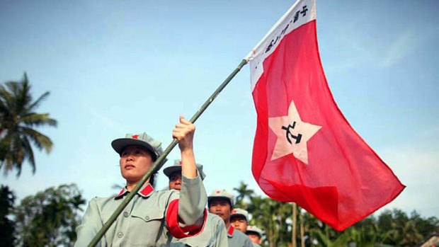 A group of 'Red Tourists' fly a communist flag as they perform a parade during a visit to a former Red Army settlement near the city of Qionghai.