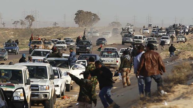 Taking cover ... rebels in Ajdabiya flee as they come under attack from elite government forces.