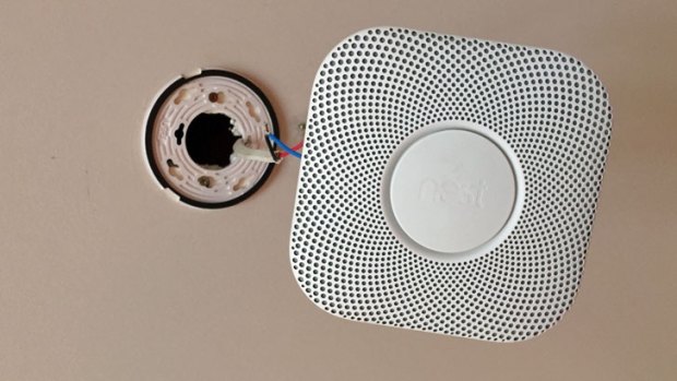 The Nest Protect hanging from the ceiling below its circular mount.