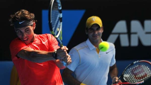 Rafael Nadal of Spain (L) is watched by Roger Federer of Switzerland as he plays a stroke during an exhibition tennis match to raise money for Queensland flood victims.