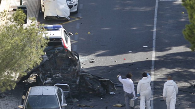 Forensics experts head towards the wreck of a car which exploded in Mallorca, killing two police officers.