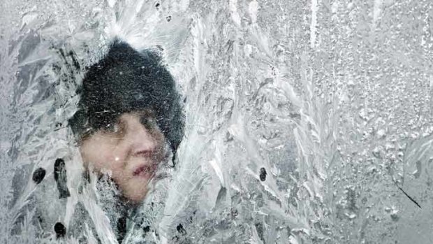Death toll from deep freeze rises... a woman looks out of a window covered in frost on a bus in Bucharest, Romania.