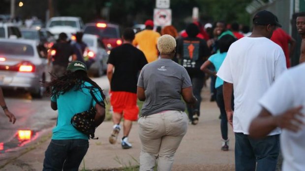 People flee as police advance on protestors firing tear gas and rubber bullets to force them from the business district into nearby neighbourhoods in Ferguson, Missouri.