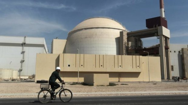 A worker rides a bicycle in front of the reactor building of the Bushehr nuclear power plant in Iran. 