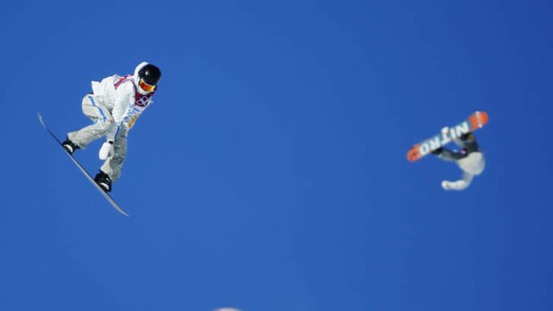 Snowboarders sail off jumps during snowboard slopestyle training.