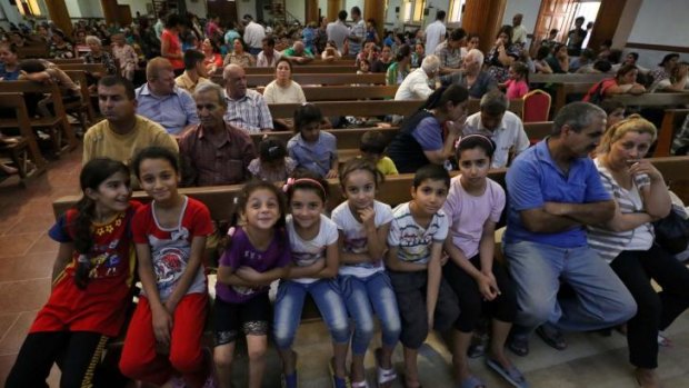 Iraqi Christians who fled the violence in the village of Qaraqush, about 30 kilometres east of the northern province of Nineveh, sit in Saint-Joseph's Church in the Kurdish city of Arbil, in Iraq's autonomous Kurdistan region, after their arrival on Thursday. Gunmen from the Islamic State (IS) have seized Qaraqush, Iraq's largest Christian town.