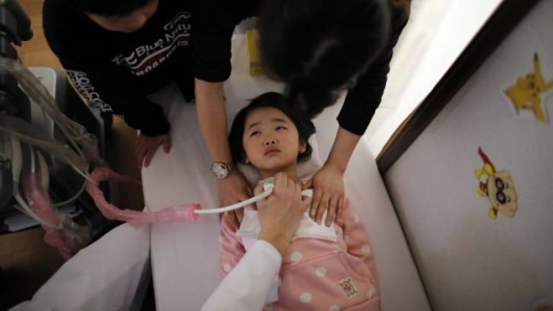 A doctor conducts a thyroid examination on five-year-old girl at a clinic in Nihonmatsu.