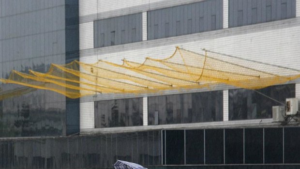 A Foxconn worker walks on a footbridge in front of nets installed to prevent workers from jumping to their deaths.