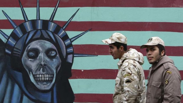 Soldiers of the Iranian Revolutionary Guard walk past a satirical mural of Statue of Liberty on the wall of the former US Embassy in Tehran.