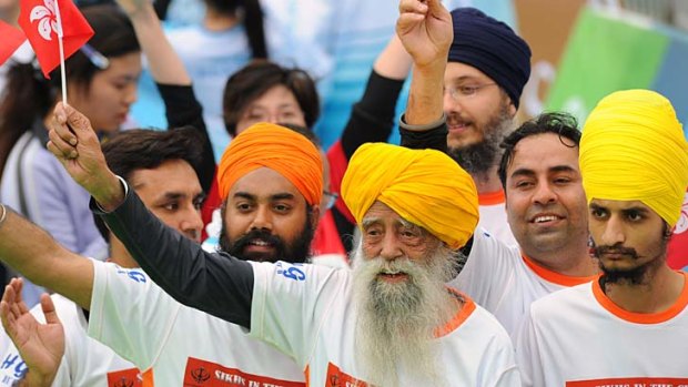Indian-born British national Fauja Singh (centre) waves a Hong Kong flag after crossing the finish line in the 10-km event as part of the Hong Kong Marathon on Sunday.
