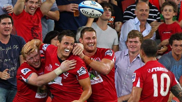 Big night out ... the Reds' Kiwi recruit Mike Harris, centre, is congratulated by  Beau Robinson, left, and James Slipper, right  after scoring against the Rebels on Friday night.