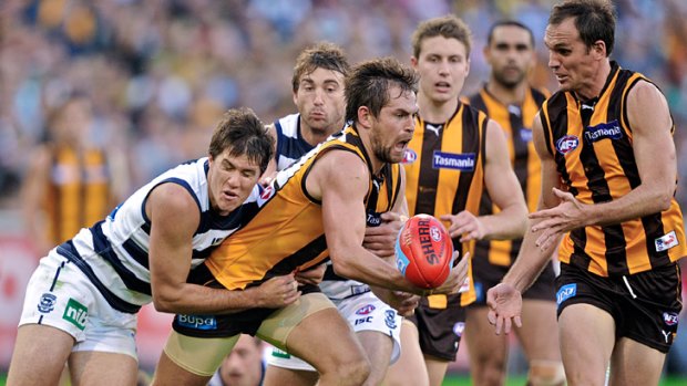 Gotcha: Hawthorn’s Luke Hodge is tackled by Andrew Mackie at the MCG.
