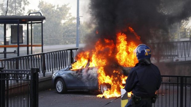Riots spreading ... a policeman and his dog walk towards a burning car in central Birmingham,.