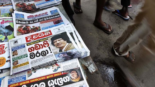 International news ... Sri Lankans walk past a newspaper stall featuring stories of Muammar Gaddafi.