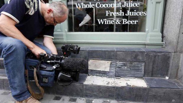 A camera man films broken slates outside a cafe in London. Local media reported the tiles had shattered from sunlight reflected by the Walkie Talkie tower in London.
