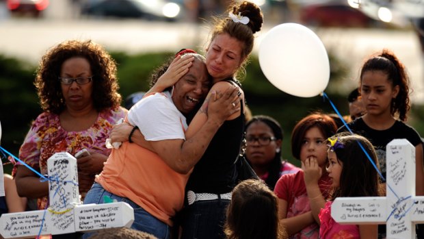 People comfort each other at a makeshift memorial near the cinema  in Aurora where the shooting took place.