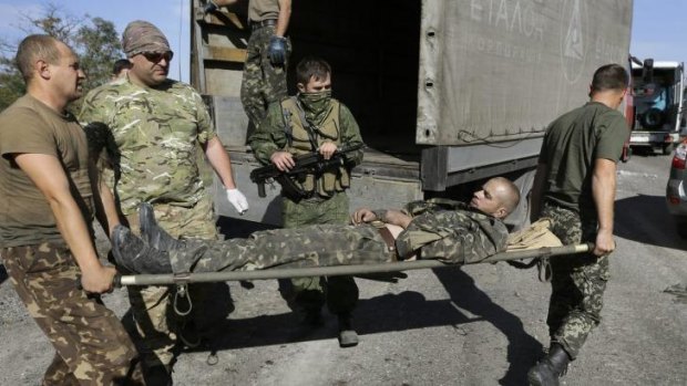 Ukrainian army personnel carry a Ukrainian government soldier injured by tank fire to an ambulance in the rebel-held town of Starobesheve, eastern Ukraine, on Saturday, August 30. 