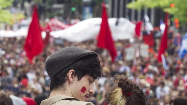 A couple watches as thousands of demonstrators march against student tuition hikes in downtown Montreal.