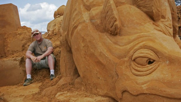 Sand sculptor Kevin Crawford with one of his creations - a gigantic stegosauras - at Dinostory, Sand Sculpting Australia's annual exhibition at Frankston.