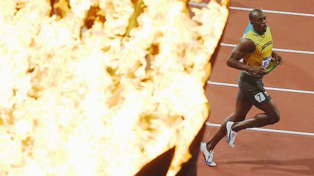 On fire: Bolt jogs past the Olympic flame as he celebrates his explosive 100m final win.