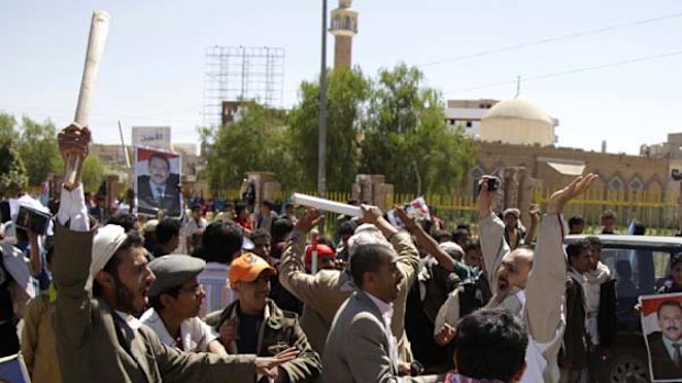 A police officer in plain clothes tries to block government backers as they chase anti-government protesters during clashes in Sanaa.