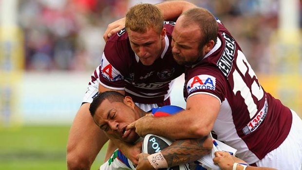 Numbers game . . .  Manly players work their aggressive defence to take down Knights centre Tafeaga Junior Sa'u at Brookvale yesterday.
