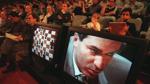 An audience watches as Garry Kasparov is shown on a TV screen contemplating his next move against Deep Blue in 1997.