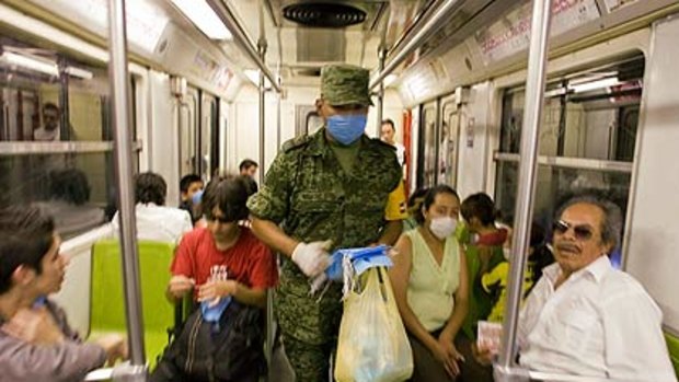 Breathe uneasy . . . a  soldier hands out masks on the metro  in Mexico City. More than 500 events have been cancelled to curtail the swine flu.