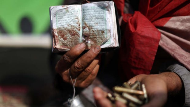 Aftermath: A protester holds a bloodied Koran and shell casings after Monday's protest massacre.