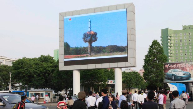 People watch a news broadcast on the launch of the solid-fuel Pukguksong-2 missile on a screen in front of the railway station in Pyongyang, North Korea.