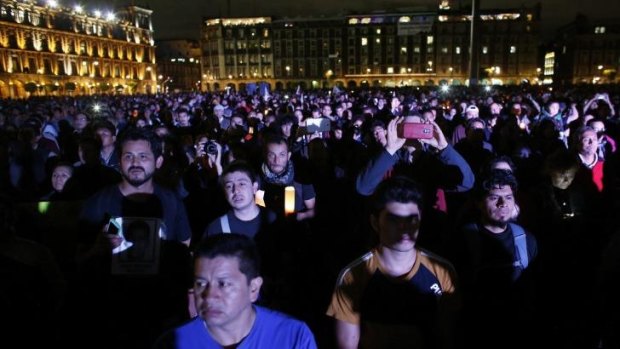 Demonstrators listen to a speech delivered by the father of one of the 43 missing students at Zocalo square in Mexico City. 