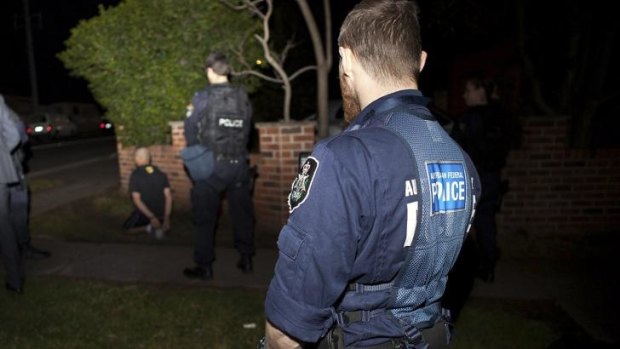 Police arrest a man as they carry out raids in Sydney. 