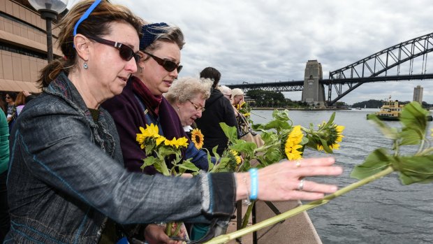 People who have been bereaved by suicide throw sunflowers into Sydney Harbour.