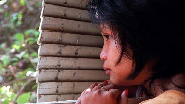 Frightened ... a 16-year-old Cambodian girl hides behind shutters after being rescued from the brothel where she was forced to work.