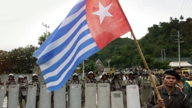 This file photo shows a West Papuan separatist carrying the banned Morning Star flag as he walks past a line of Indonesian riot police officers surrounding a pro-independence celebration in Jayapura, Irian Jaya.