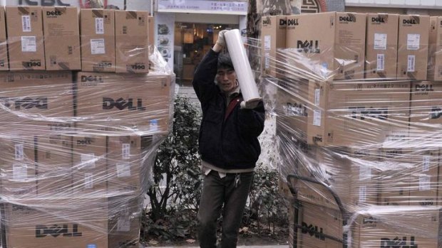 A worker uses a roll of plastic tape to secure Dell boxes at a street near an electronic products market in Nanjing, China on March 7, 2012.