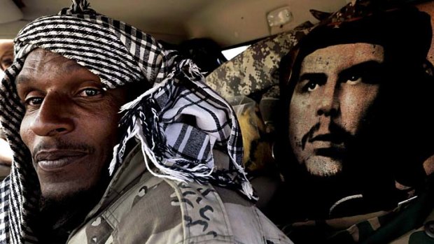 A Libyan rebel sits in his vehicle next to an image of  Cuban revolutionary Che Guevara as rebel forces push towards Gadaffi's hometown of Sirte.