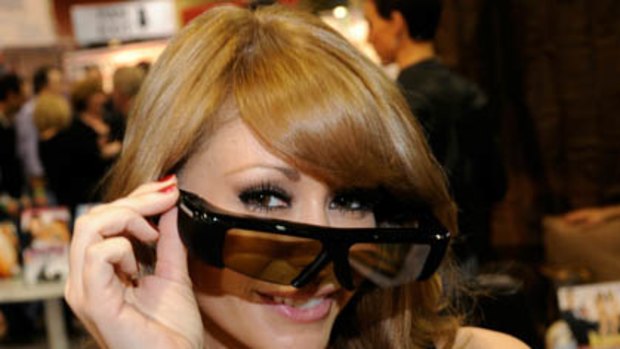 Adult film actress Monique Alexander displays polarized 3D glasses at the Funky Monkey Movies booth at the 2011 AVN Adult Entertainment Expo.