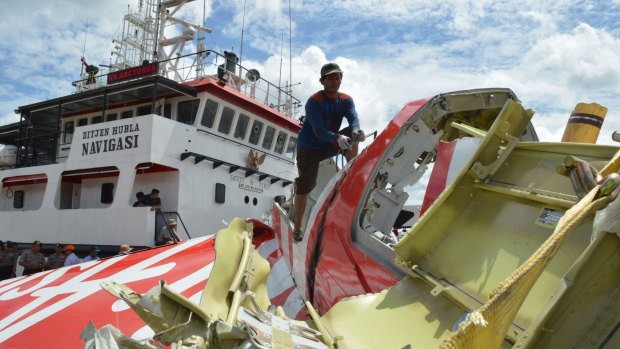 An Indonesian worker cuts the tail of the AirAsia flight QZ8501 in Kumai on Monday after debris from the crash was retrieved from the Java sea.