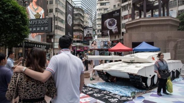 Pedestrians in Hong Kong observe a tank replica displayed to symbolise the 1989 military crackdown in Tiananmen Square.