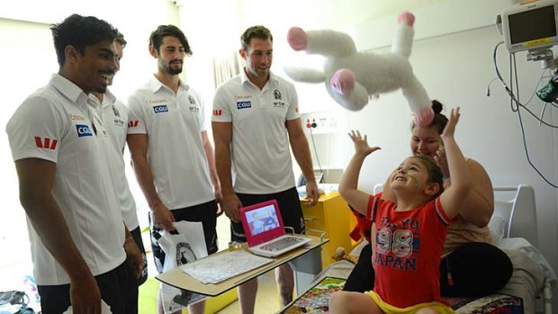 Magpies Tony Armstrong, Jesse White, Brodie Grundy and Travis Cloke observe the marking style of five-year-old Abbey McAliece and her mum Shayna at the Royal Children's Hospital.