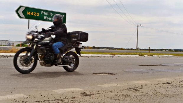 Danger: A rider negotiates potholes on the Bass Highway. Thousands of motorcyclists will travel along the route to Phillip Island this weekend.