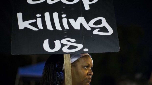 Natasha Gray holds a placard as she gathers with other protesters across the street from the police department in Ferguson, Missouri.