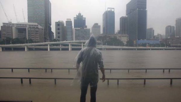 A man watches the Brisbane River rise.