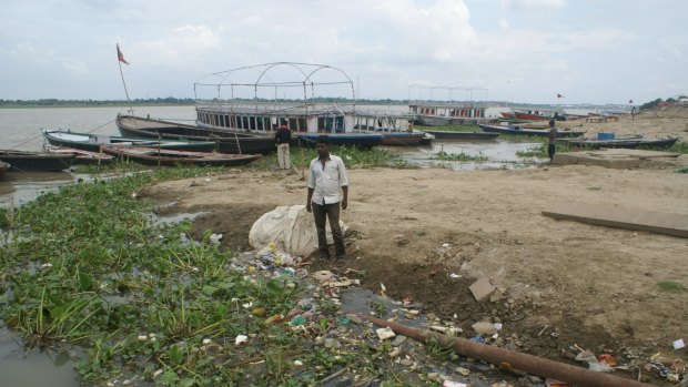 Boatman Virender Nishad and the rubbish by the river bank.