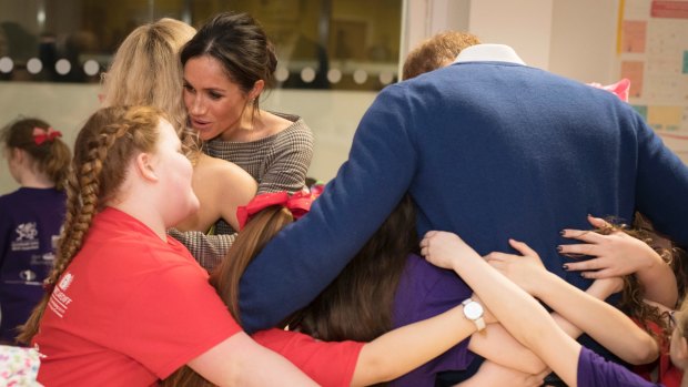 Britain's Prince Harry and Meghan Markle, 2nd left, receive a group hug from the children of a street dance class during their visit to Star Hub, a community and leisure centre in Cardiff, Wales, on Thursday Jan. 18, 2018. 