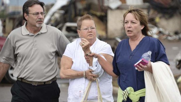 A women is helped with a arm injury suffered after a tornado destroyed buildings and overturned cars in Moore, Oklahoma May 20, 2013.