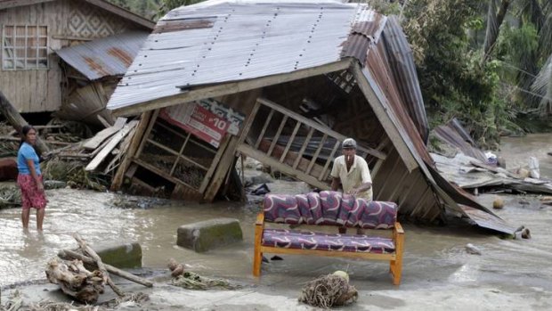 Residents clean their sofa outside their destroyed house after Typhoon Bopha hit Compostela Valley, southern Philippines