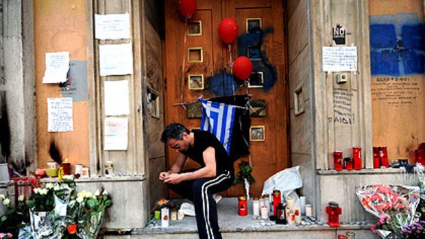 A man lights a candle at Athens' Marfin Egnatia Bank where a firebomb killed three people amid last week's street protests over government austerity measures.